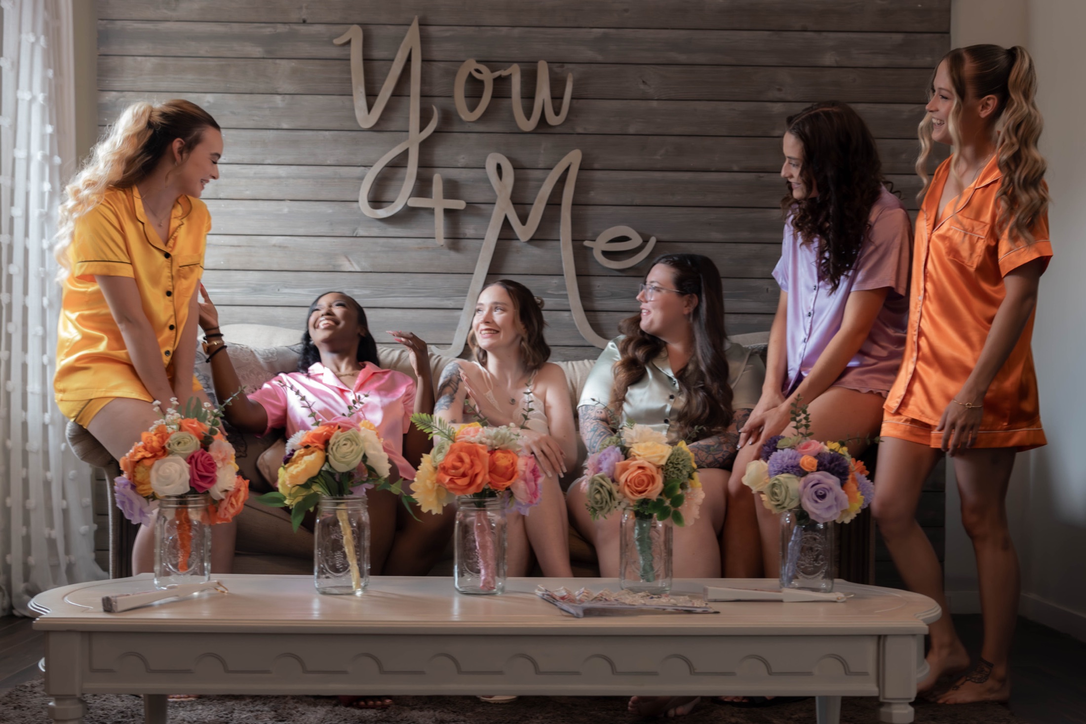 Bride laughing with her bridesmaids in colorful silk pajamas