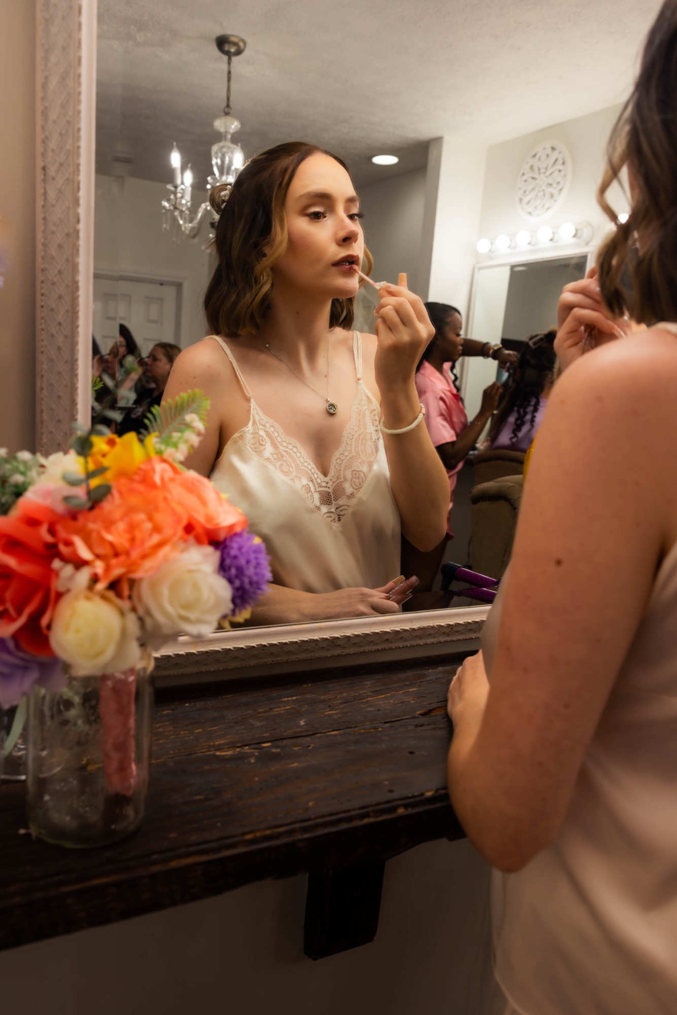 Bride applying lipstick at a mirror while getting ready