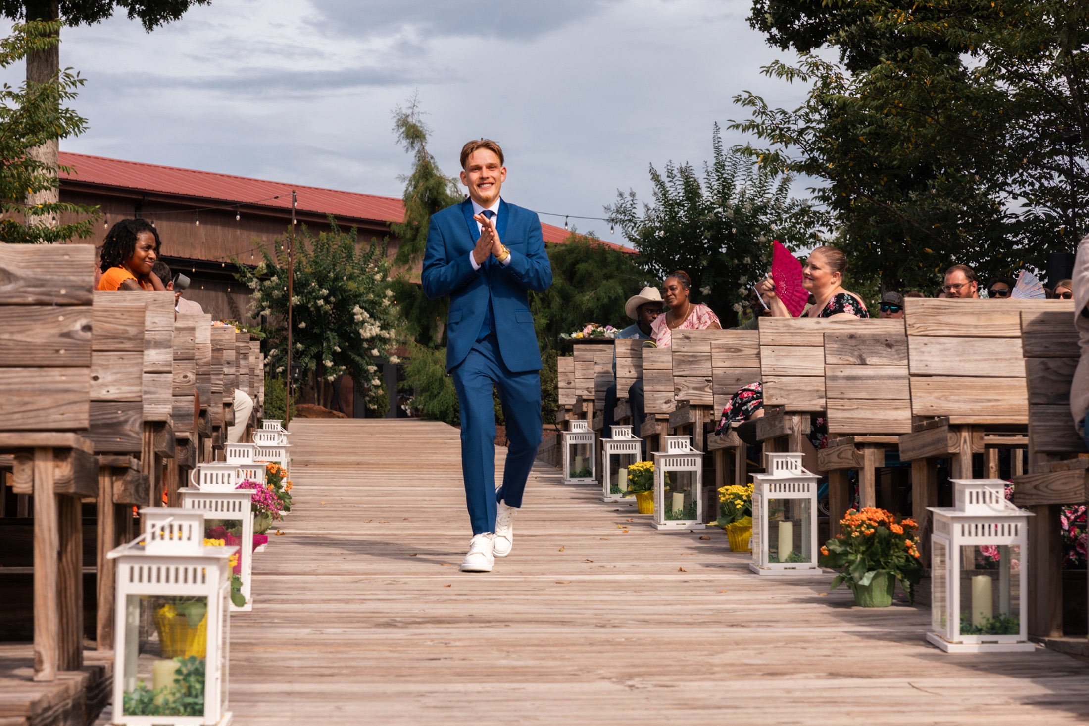 Groom smiling as he walks down an outdoor ceremony aisle