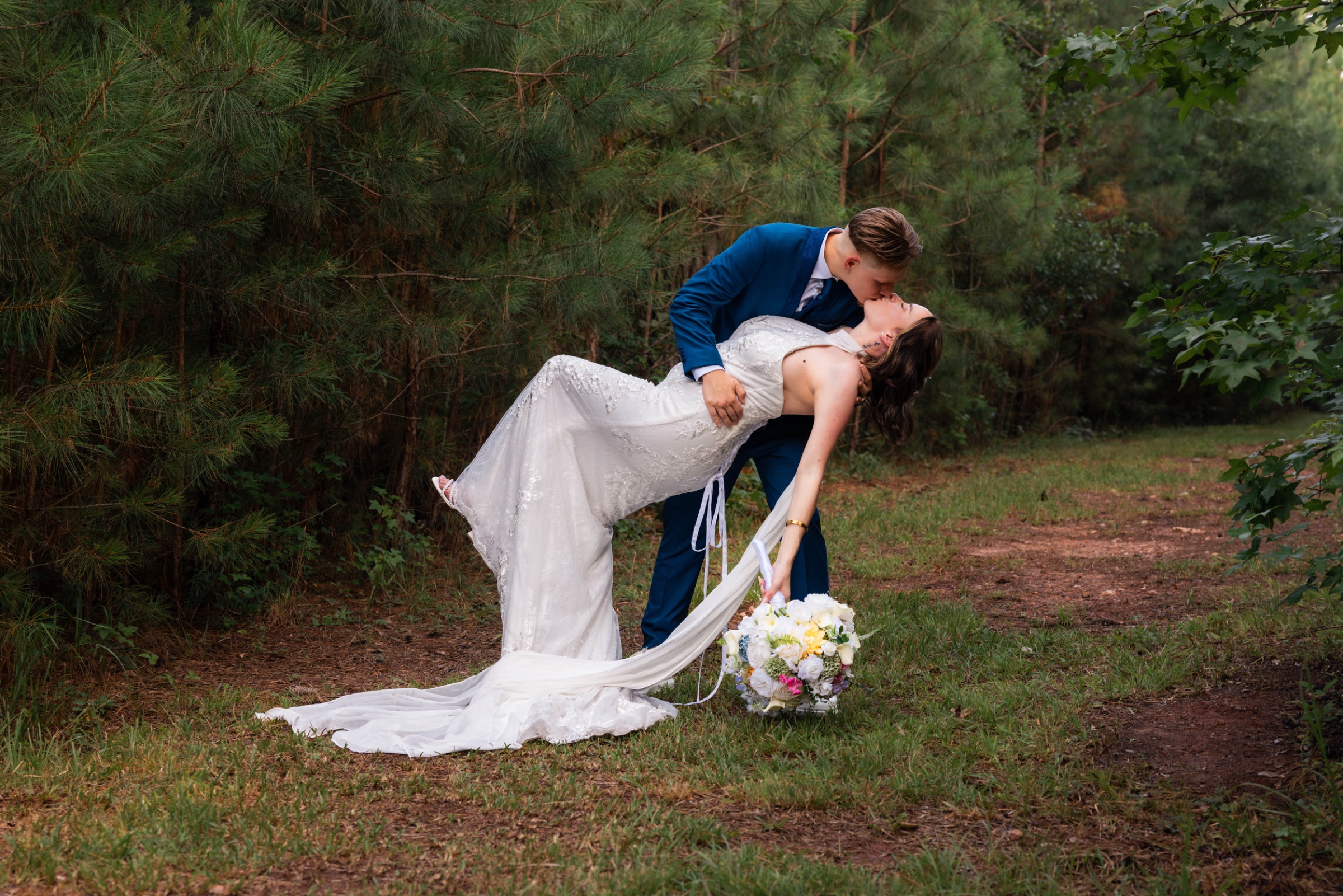 Newlyweds sharing a kiss beneath the trees