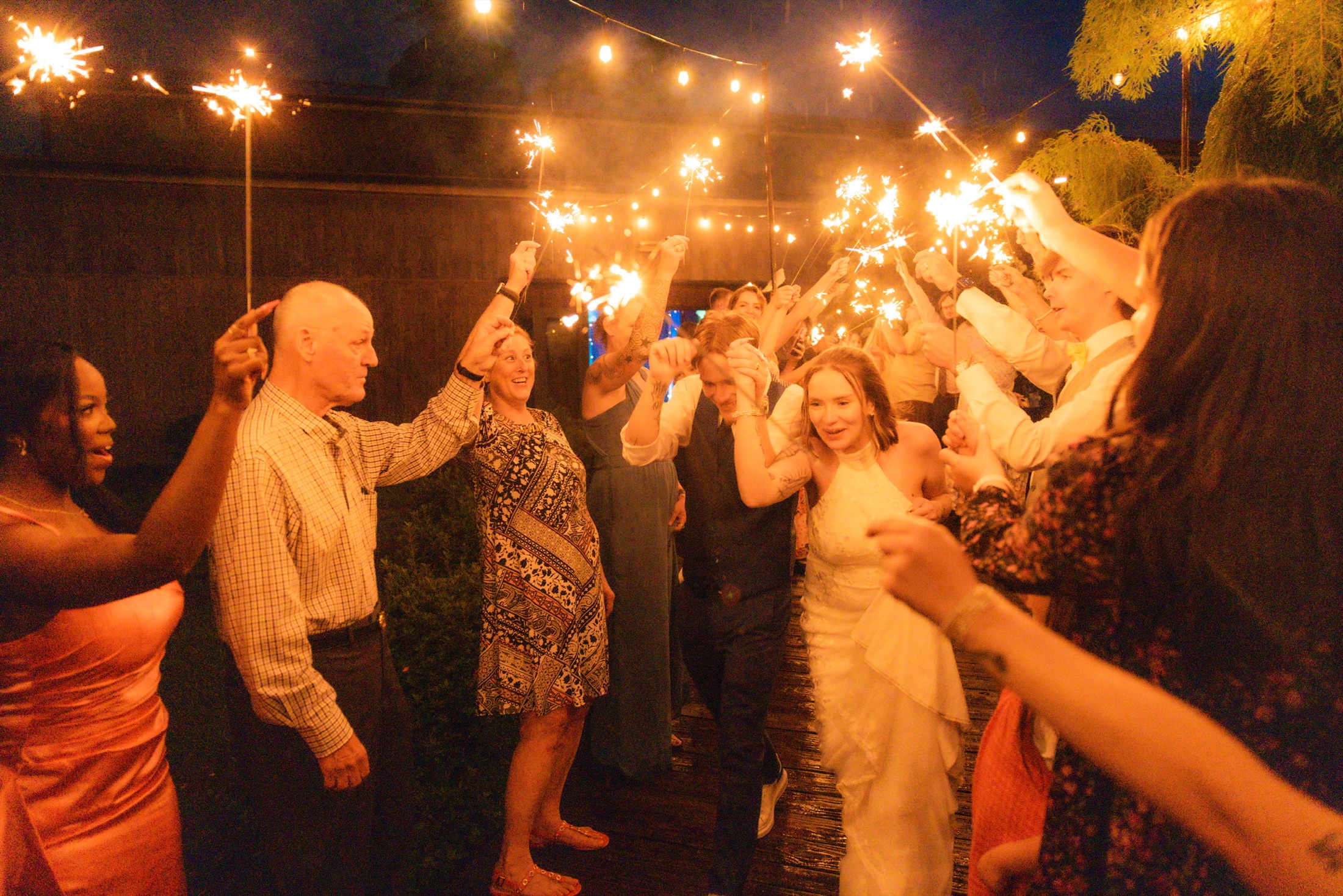 Newlyweds running through a sparkler exit with their guests